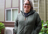 Jenni Treadway of Issaquah stands smiling in front of her new heat pump.