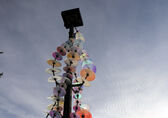 One of the installations that is part of "River" at Crossroads Park features colored glass disks threaded on metal wires draped around a light pole. lass