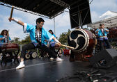 A man strikes a big taiko drum on a stage.