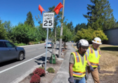 Workers walk away from a 25-mph speed limit sign they just installed by a Bellevue streeet.