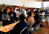 City staff at tables on the City Hall concourse meet with people walking around the space.
