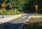 A woman walks in a crosswalk that has flashing beacons.