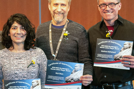 a woman and two smiling men holding certificates of appreciation