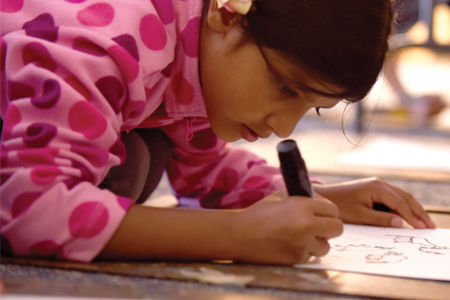 girl in a pink polka dot top drawing