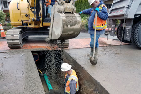 Two man and a backhoe replacing sewer