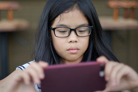 young girl of asian descent watching a movie on her phone