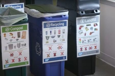 Photo of garbage, recycling and compost bins with signage in a commercial building