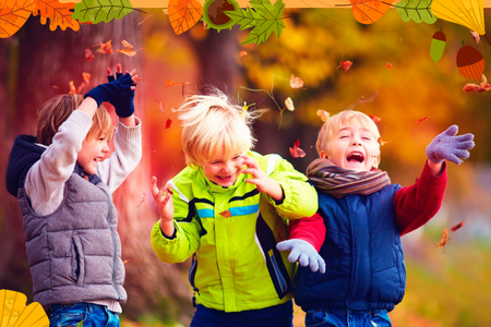 3 young children standing next to each other, with an autumn background