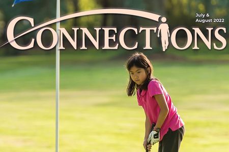 Cover of July-August 2022 Connections program brochure, featuring young girl with black hair, wearing a bright pink shirt and a golfing glove, putting a golf ball at the Crossroads Par 3 Golf Course