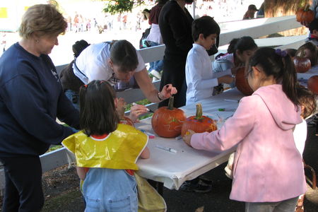 Children and adults decorating pumpkins at a table