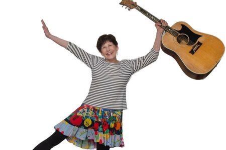 Nancy Stewart holds guitar in one hand and smiles at camera