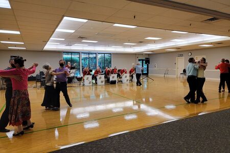 Several seniors dancing in pairs to lively swing music inside North Bellevue Community Center