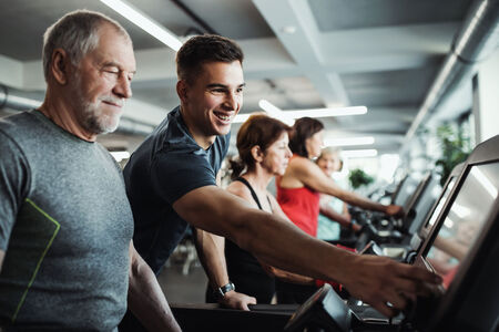 A group of seniors in gym with a young trainer doing cardio work out.