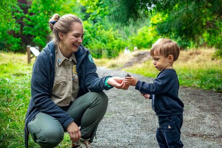 Park Ranger shows a pine cone to a child during a nature walk