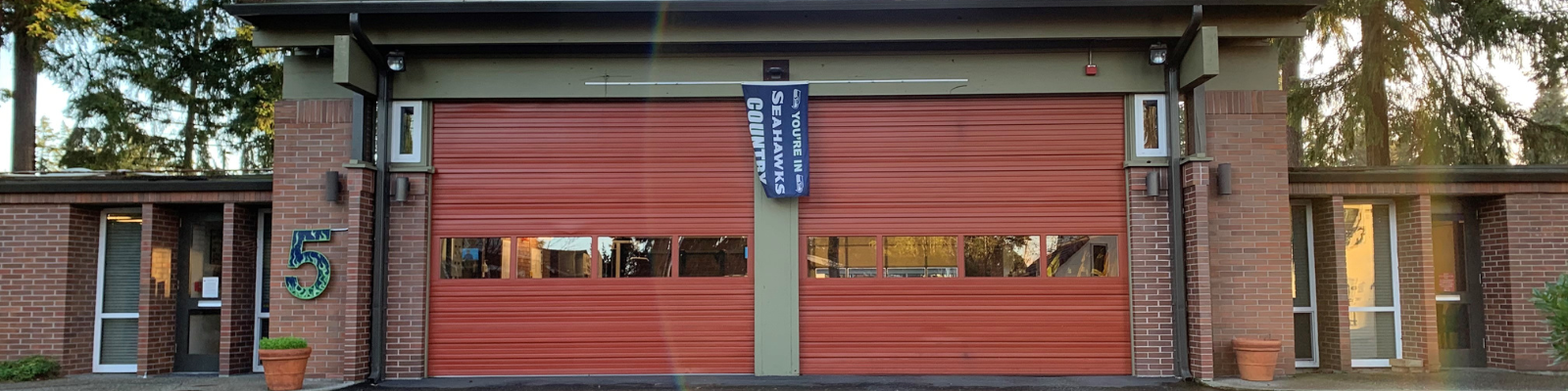 Image of Bellevue Fire Station 5, which is a one story brick building with two rust red garage doors. 