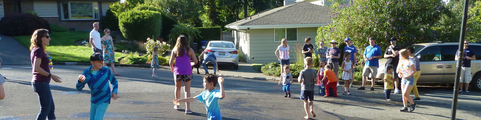 Neighborhood block party where children and adults gather on a residential street.