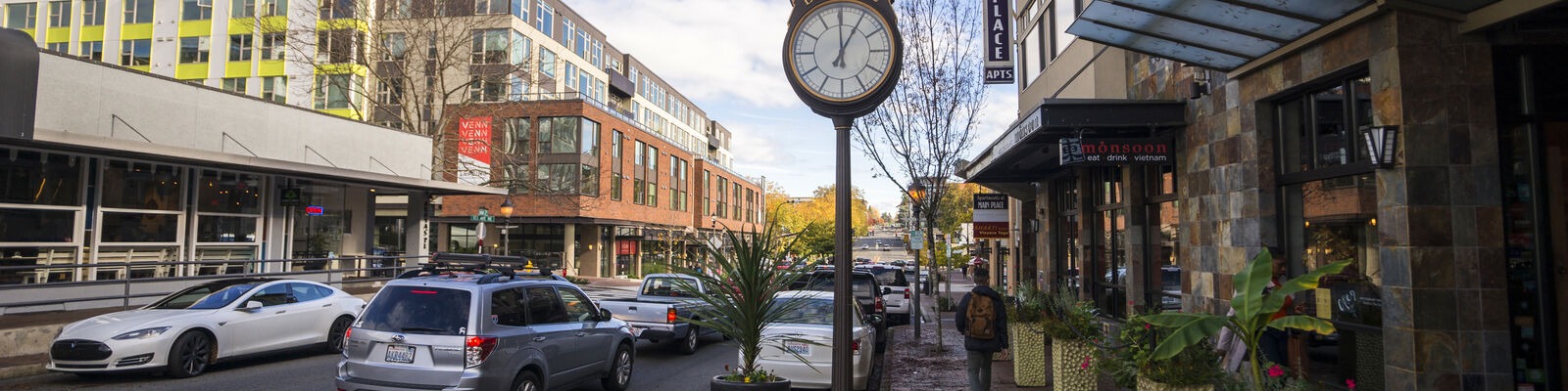 Clock on Main Street with cars driving by.