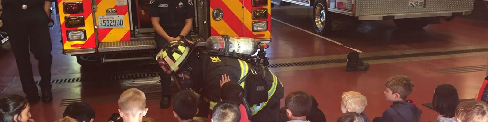 A Bellevue firefighter demonstrates how to crawl below smoke to a group of young children. 