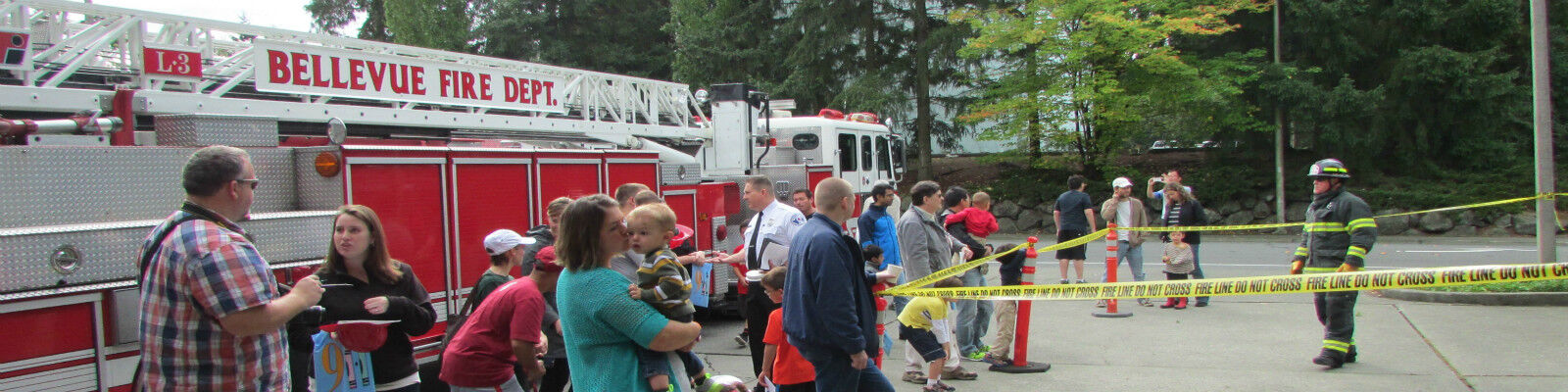 Community members gathered around a fire prevention officer as they give a stove top fire demonstration.