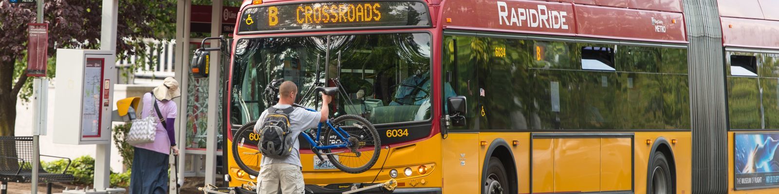 Image of a person placing a bicycle on the bike rack of a King County Metro RapidRide bus