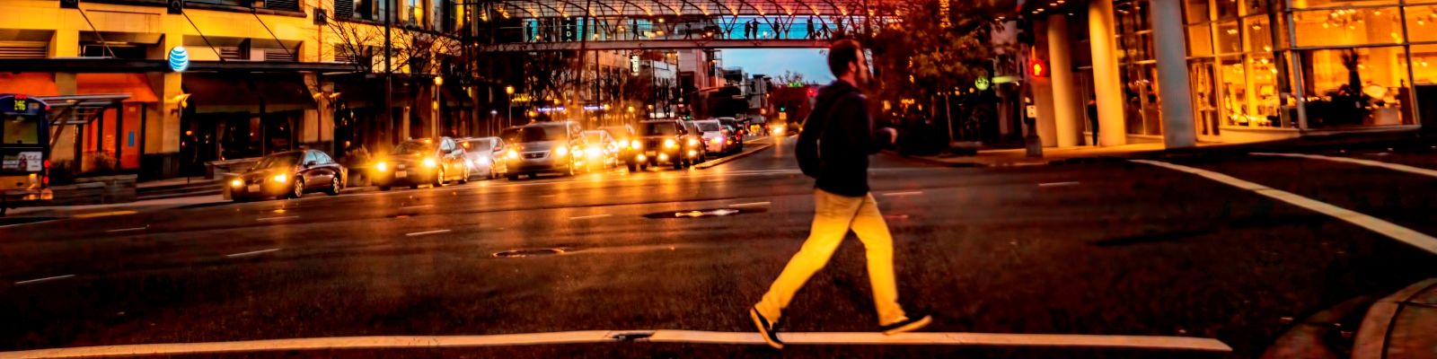 Image of a pedestrian crossing a street, a public right-of-way, at night