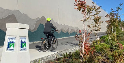 A cyclist uses the Mountains to Sound Greenway trail in Factoria, where bas-relief mountains decorate the retaining wall.