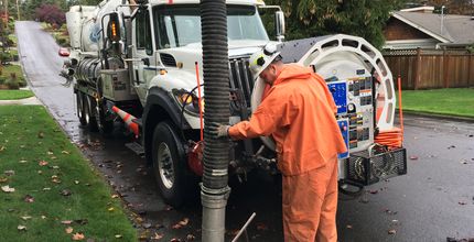 Utilities staff use a vactor to clear a catch basin.