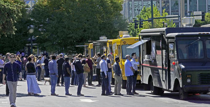 People line up for food trucks parked downtown.