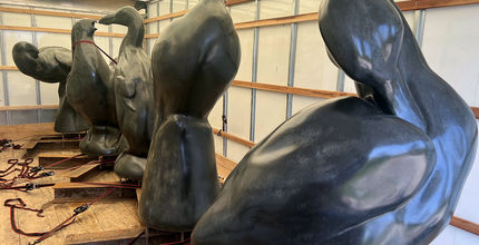 Large sculptures of extinct birds are in a wood-framed, canvas storage box.