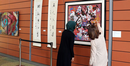 People look at an painting hung at City Hall for the Asian American Native Hawaiian and Pacific Islander heritage celebration.