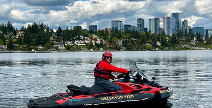 A firefighter rides a jet ski in Lake Washington, with downtown Bellevue in the background.