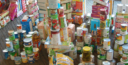 A variety of canned and boxed food is stacked up in a pile.