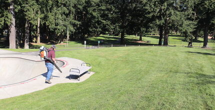 A man with a leaf blower tends to Crossroad Park.