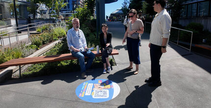 Four people look at a sidewalk decal in downtown Bellevue.