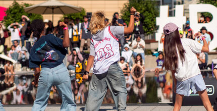 Young people dance in front of a crowd on the City Hall plaza.