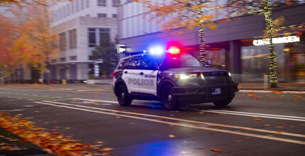 A Bellevue police SUV with lights flashing proceeds along 108th Avenue Northeast in downtown Bellevue.