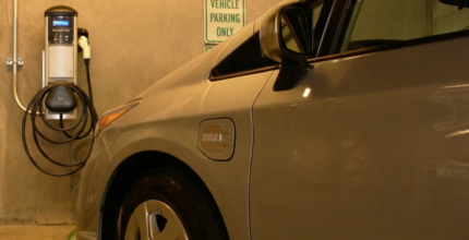An electric vehicle is plugged into a parking garage charging station.