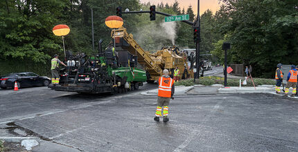A paving machine runs past 112th Avenue Southeast.