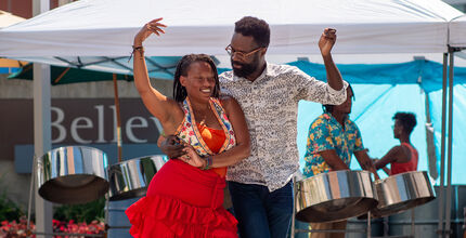 A couple dances, with a band behind them under a canopy, at Swing Arts Foundation's free jazz and swing dance lesson social at City Hall Plaza. 