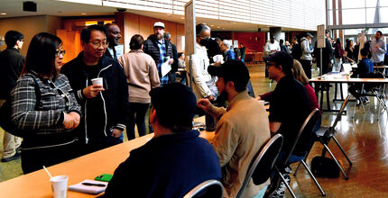 City staff at tables on the City Hall concourse meet with people walking around the space.