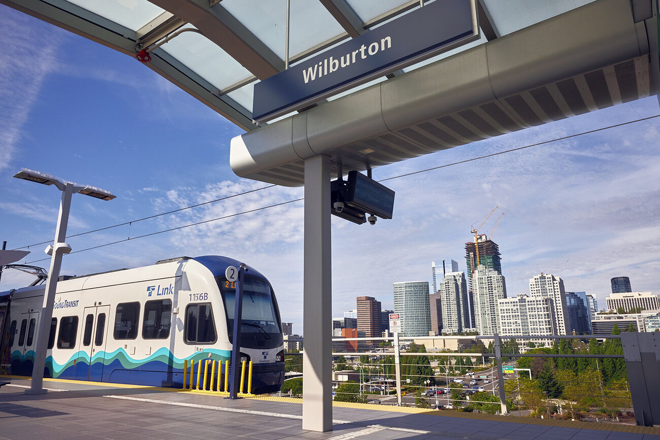 A light rail train arrives at the Wilburton station with downtown in the background.
