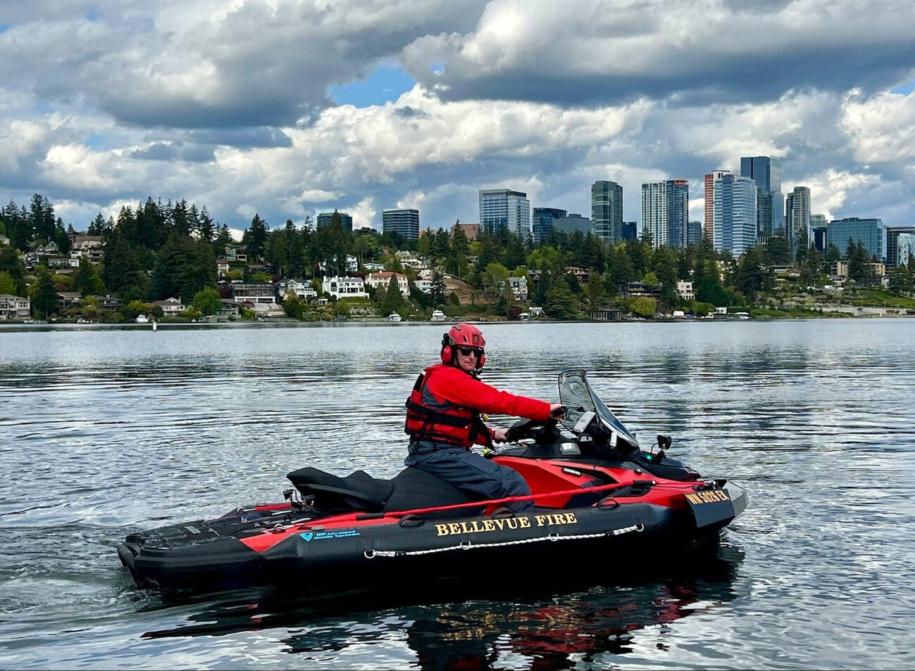 A firefighter rides a jet ski in Lake Washington, with downtown Bellevue in the background.