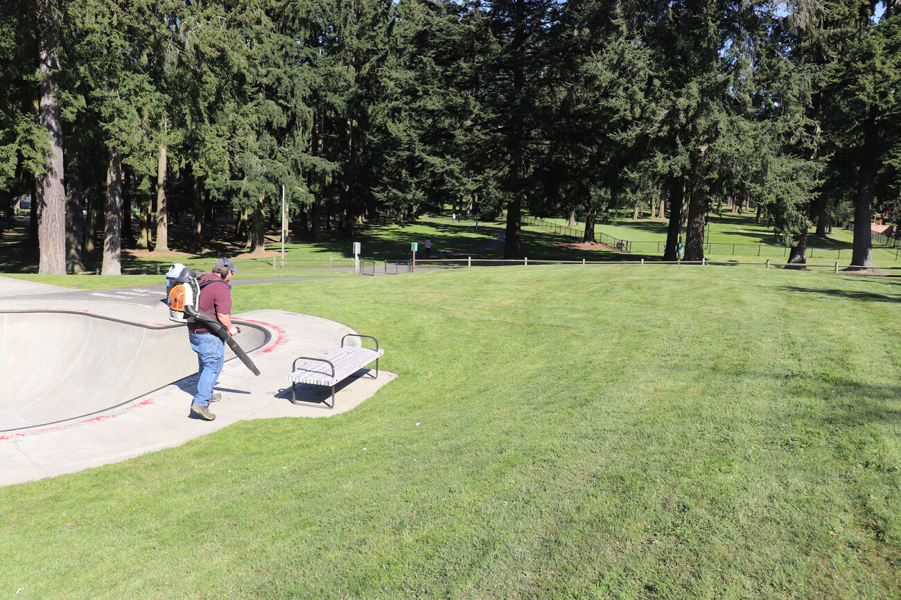 A man with a leaf blower tends to Crossroad Park.
