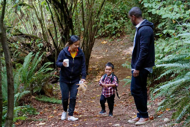 A man, woman and child walk along a forest trail.