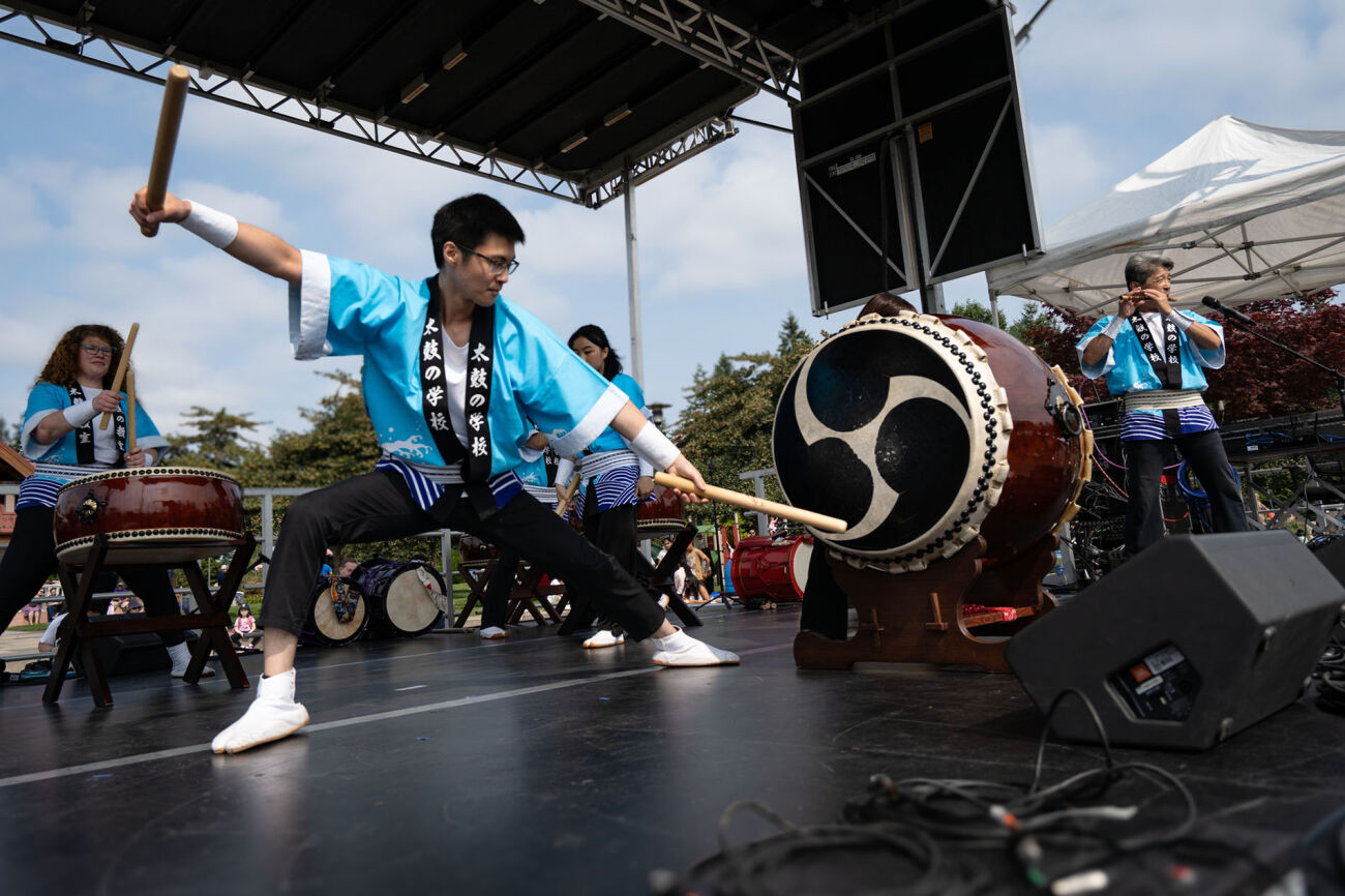 A man strikes a big taiko drum on a stage.