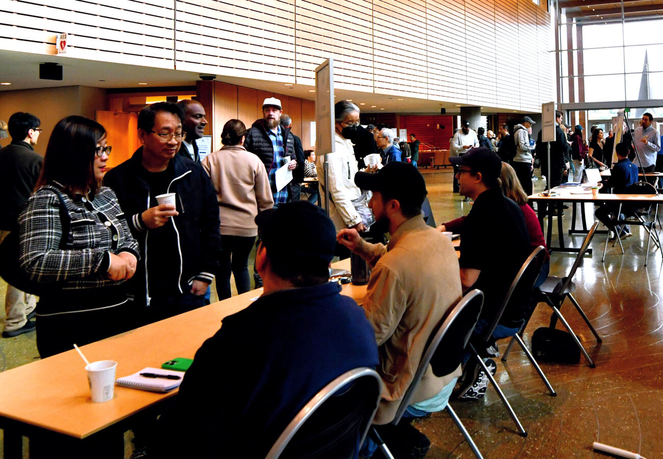City staff at tables on the City Hall concourse meet with people walking around the space.