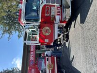 Image of Bellevue Fire Engine 105 outside of Station 5 in Clyde Hill with the doors open and visitors checking out the compartments. 