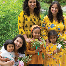 Three women and thee children in yellow dresses smiling