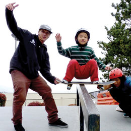 Two young adults teaching a child to skateboard