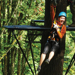 A smiling girl sliding down a zip-line